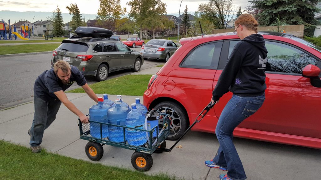 Sarah and Tyler go up the hill after fetching many carboys of water.