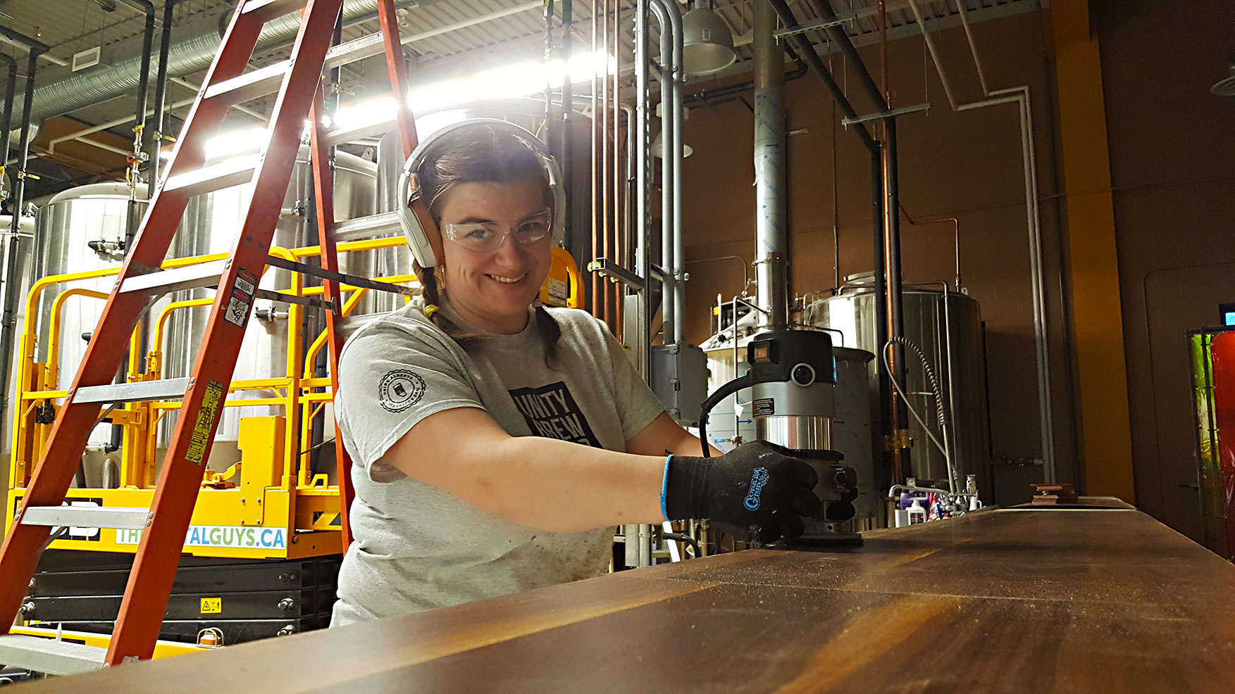 Founder Laura uses a router to trim countertop laminate on our brewery pony wall prior to our opening.