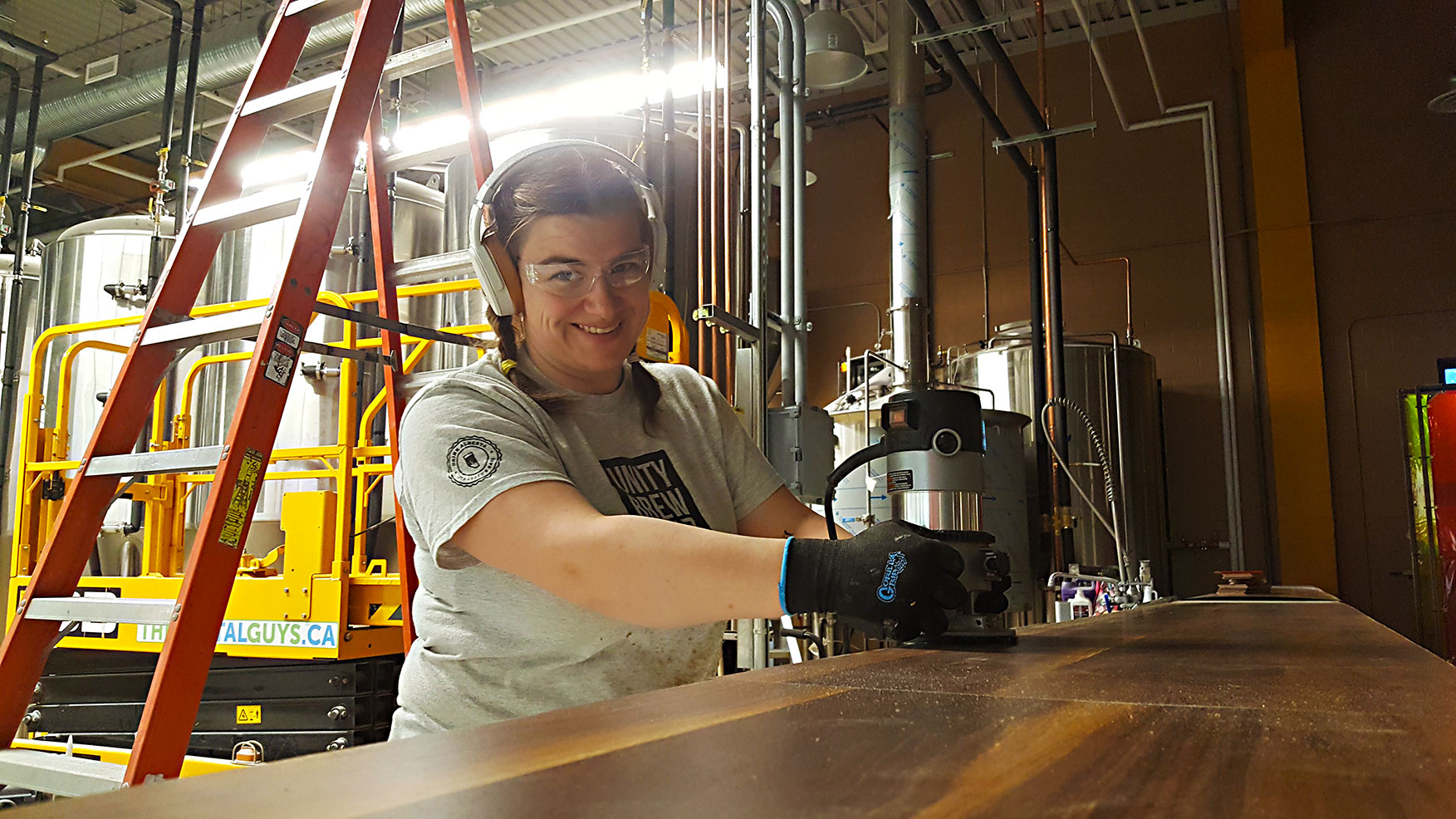 Laura Trimming Countertop Founder Laura uses a router to trim countertop laminate on our brewery pony wall prior to our opening.