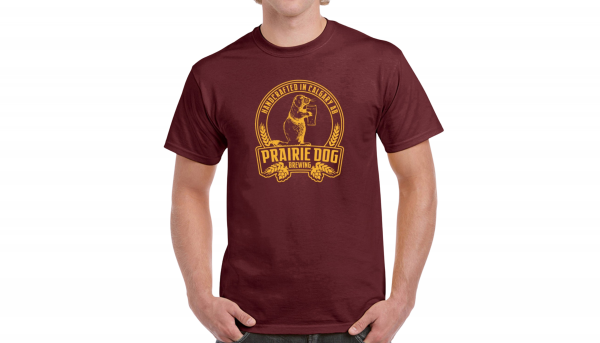 A man wearing a maroon coloured t-shirt with the Prairie Dog Brewing badge on the front in gold.