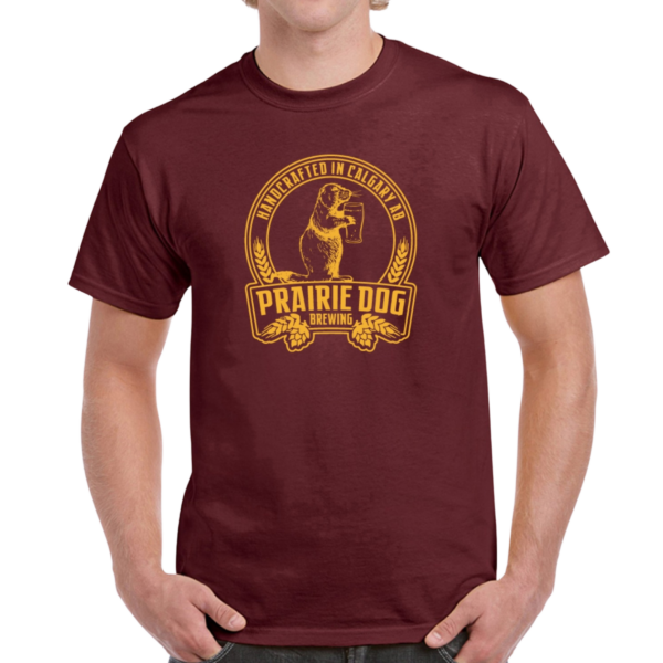 A man wearing a maroon coloured t-shirt with the Prairie Dog Brewing badge on the front in gold.