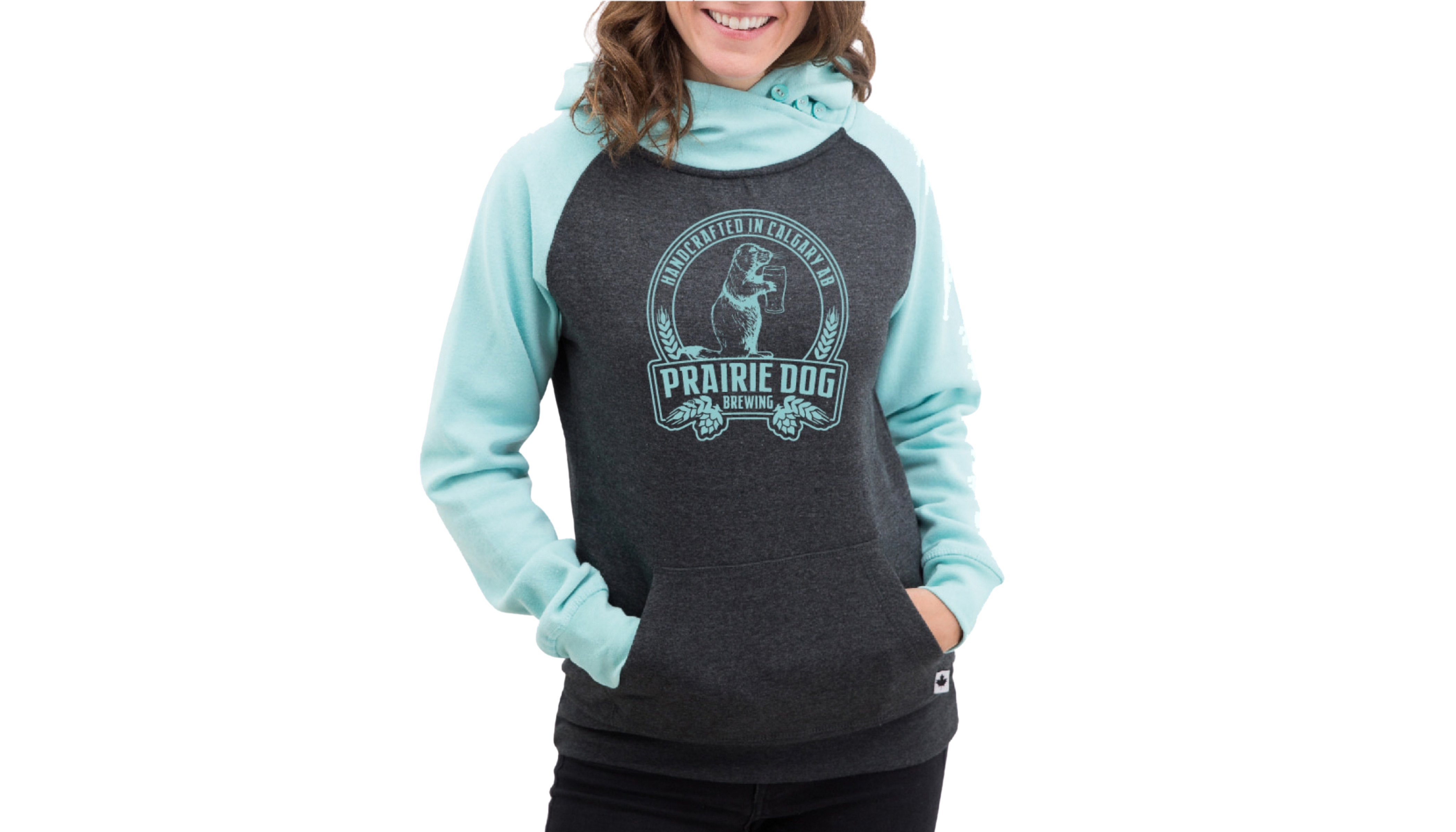 A woman wearing a hoodie with teal sleeves and hood, a dark grey torso with the Prairie Dog Brewing badge in light gray on the front.