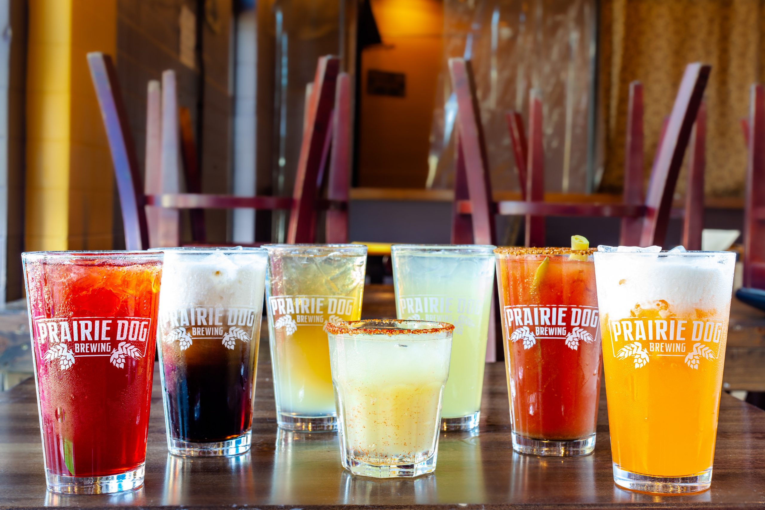 An assortment of Prairie Dog Brewing cocktails. From left to right: Black Cherry Gin Rickey, Root Beer Swirl, Prairie Mule, Chili Margarita (front), Bourbon Lemonade, Prairie Caesar, and Creamsicle.