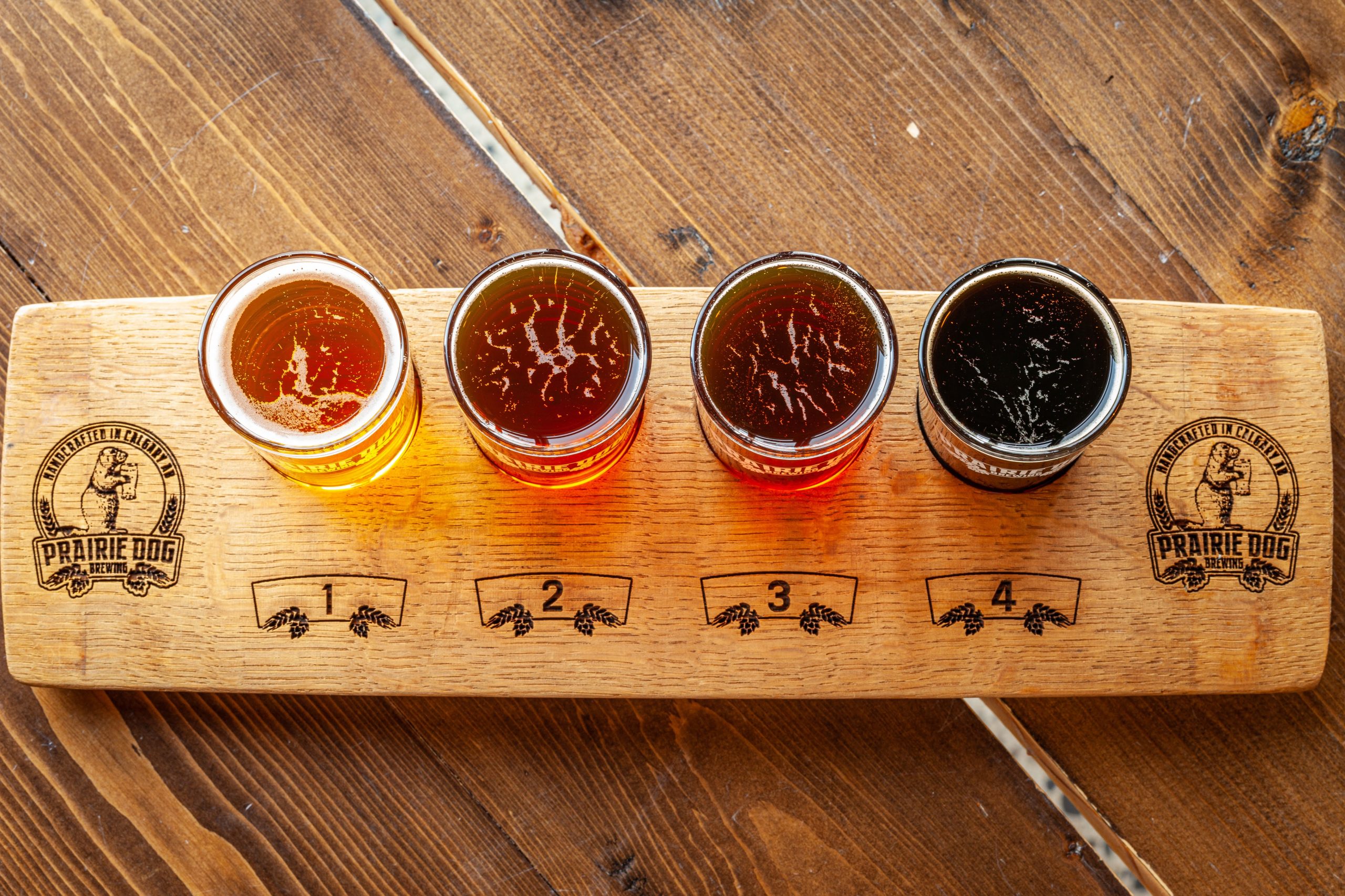 A Prairie Dog branded oak stave flight paddle with four different beers