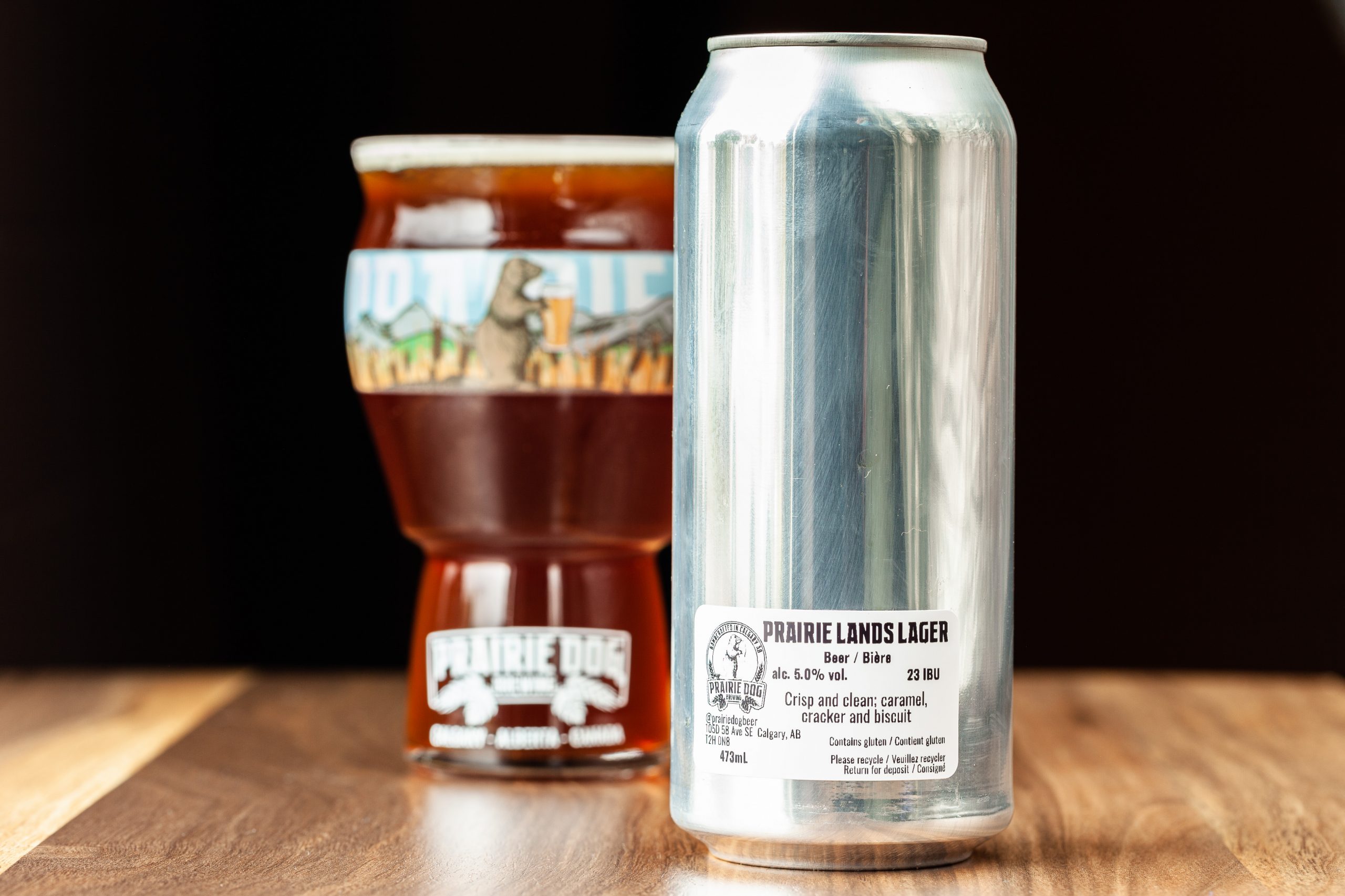A 473-mL can of Prairie Dog Brewing Prairie Lands Lager, a Vienna-style lager, with a glass of the beer in the background.