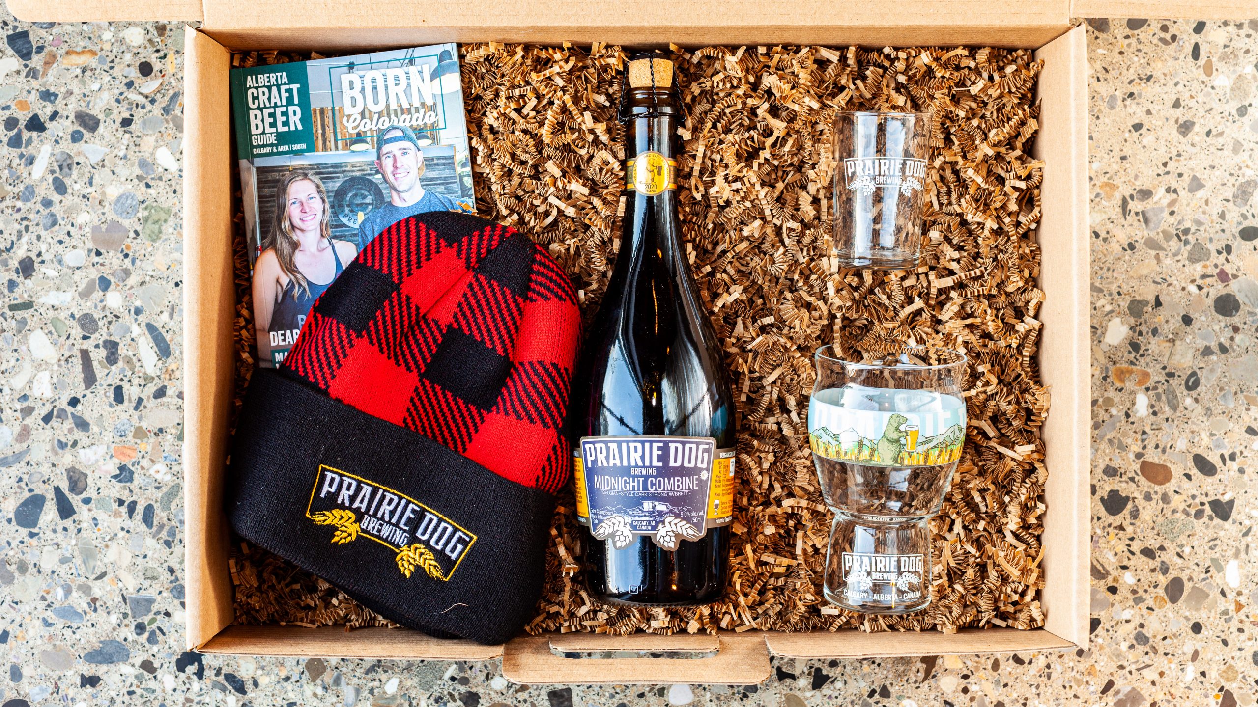 Prairie Dog Brewing Super Fan Holiday Beer Gift Combo Box Set, including our premiere 2020 release of Midnight Combine, a Belgian-style barrel-aged dark strong ale, a 16-oz Prairie-Dog-branded Craftmaster Grand beer glass, a 5-oz Prairie-Dog-branded taster glass, a red plaid lumberjack toque with embroidered Prairie Dog Brewing logo, and the latest Alberta Craft Beer Guide (southern Alberta).