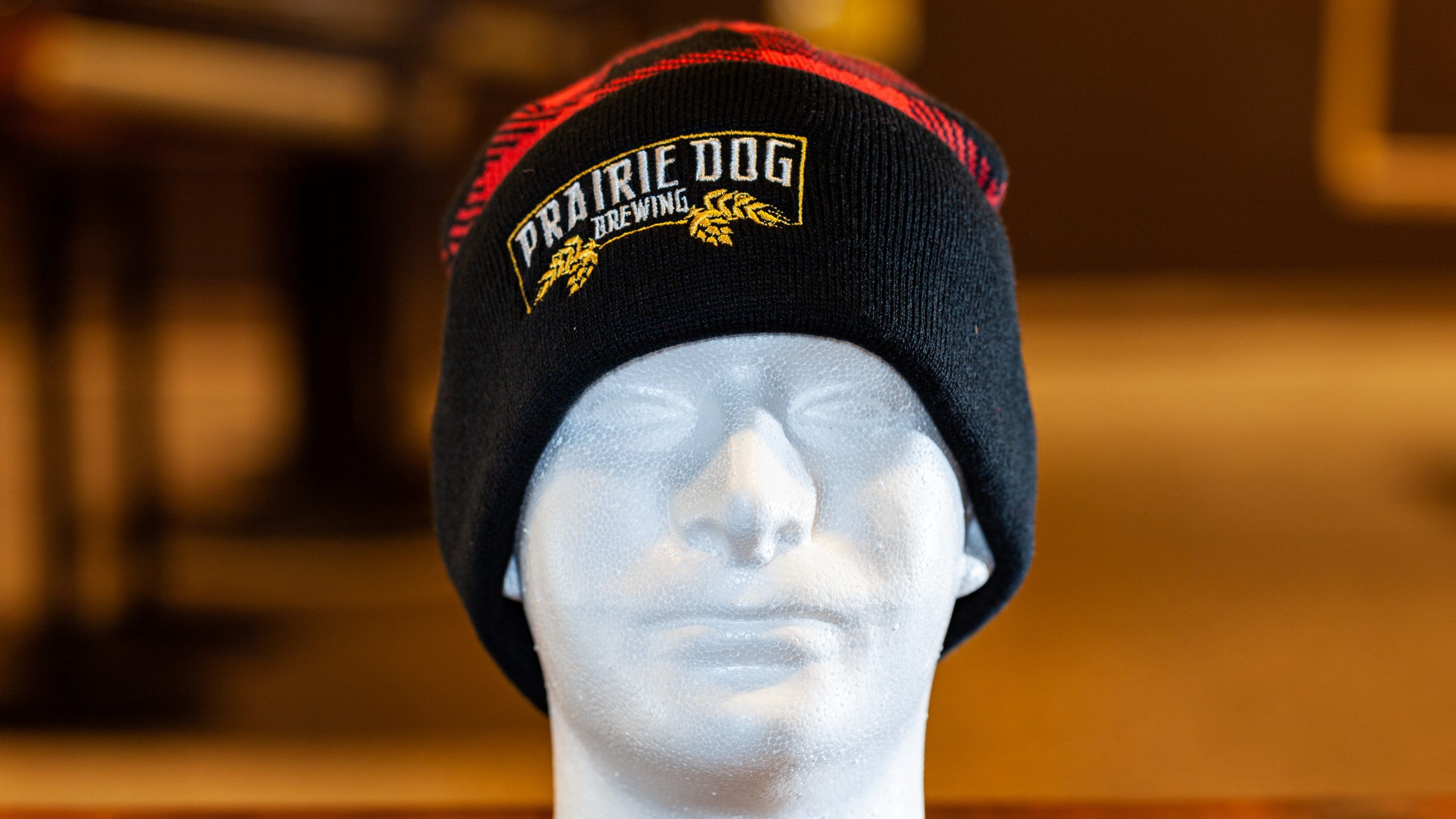 A red lumberjack-style toque with a black brim and embroidered Prairie Dog banner on the brim. Unisex. 1-size fits all.