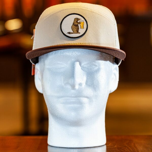 Prairie Dog Brewing trucker hat by Pukka. These hats feature a cream-coloured cotton twill front with a button-style Alby mascot logo, with a brown cotton brim. Cream-coloured trucker mesh and snap-back.