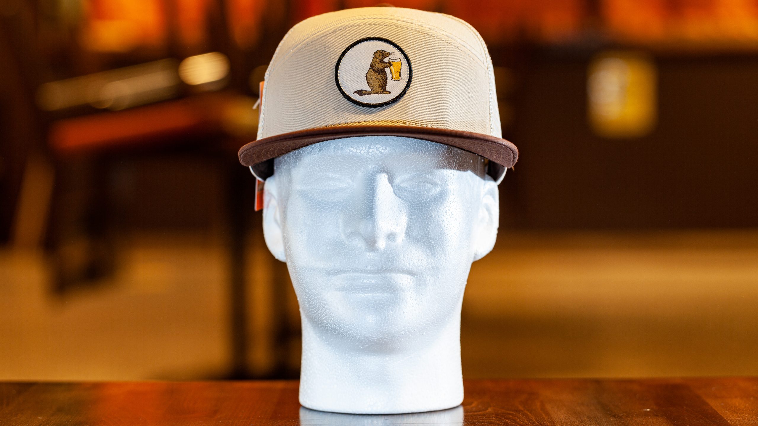 Prairie Dog Brewing trucker hat by Pukka. These hats feature a cream-coloured cotton twill front with a button-style Alby mascot logo, with a brown cotton brim. Cream-coloured trucker mesh and snap-back.
