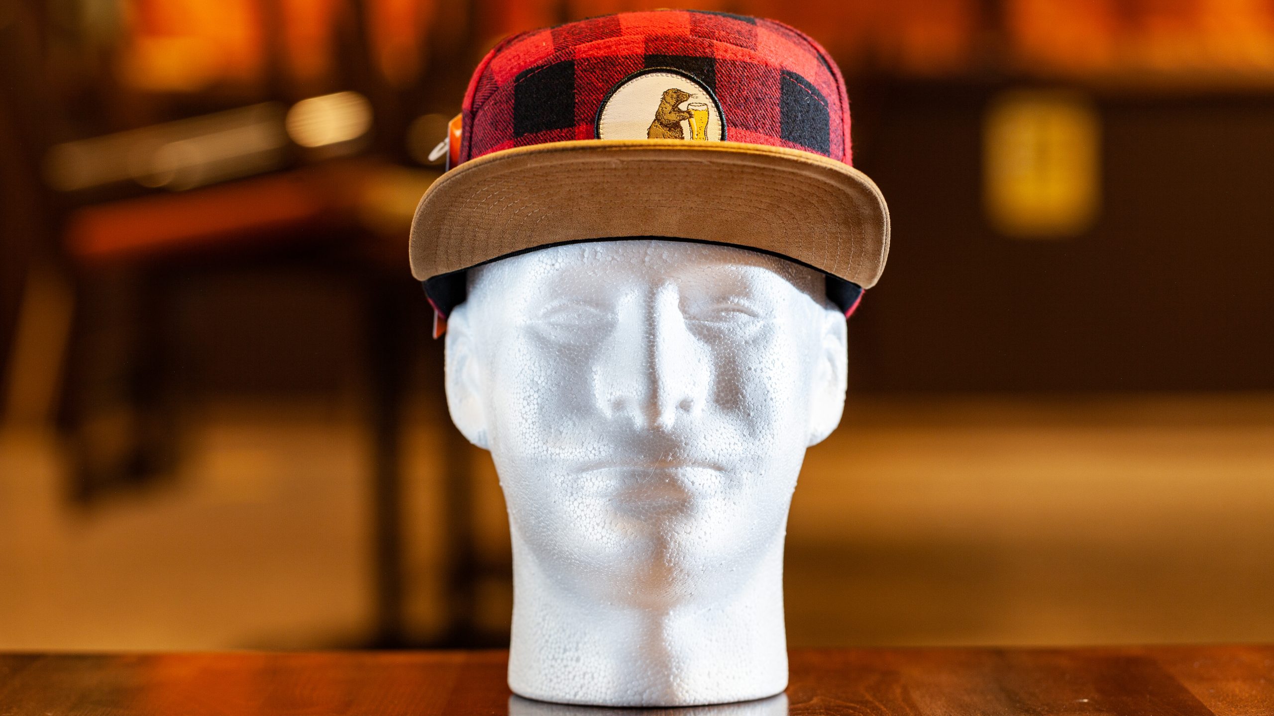 A Prairie Dog Brewing branded red and black Buffalo-check (plaid) hat, made by Pukka. The hat features our mascot Alby on a round embroidered button. Brown suede brim with snap-back.