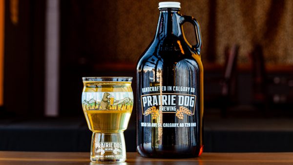 A 16-oz pint pour of Uncommon Dry Apple Cider (Gluten Free) along with a 64-oz growler jug, at Prairie Dog Brewing.