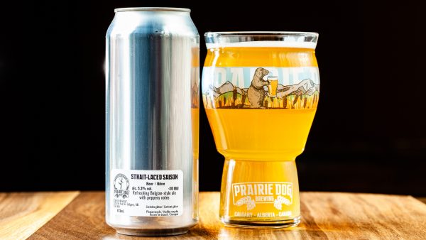 Prairie Dog Brewing's Strait-Laced Saison in a 473mL can and a 473mL branded beer glass.