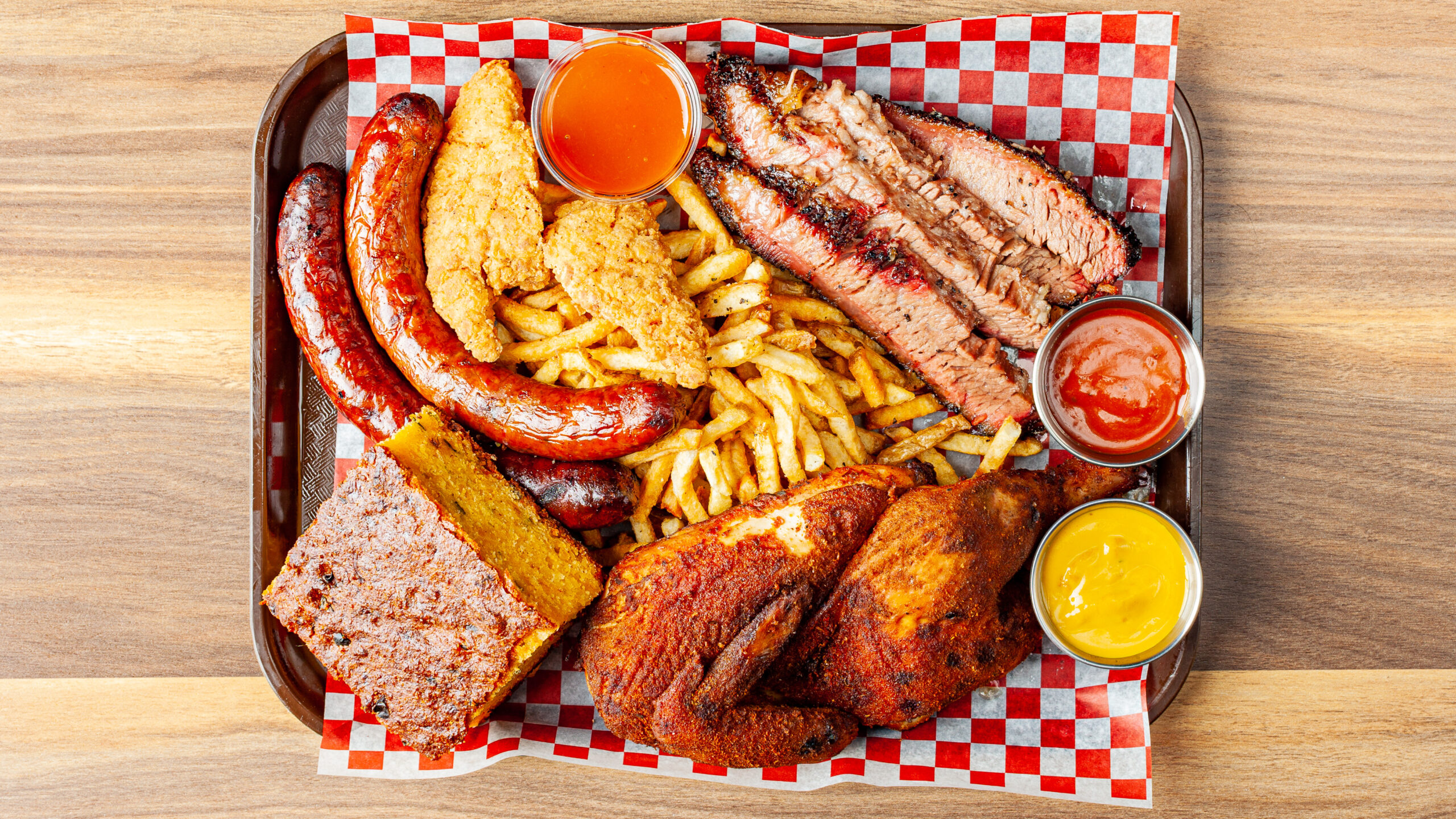 Prairie Dog Brewing's Coterie BBQ platter with chicken, brisket, chorizo sausage, chicken tenders and two sides and sauces.