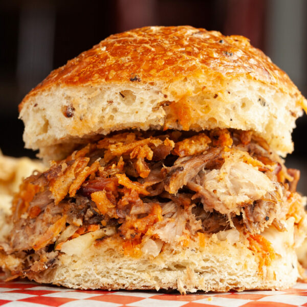 Kids pulled pork sandwich with fries in the background.