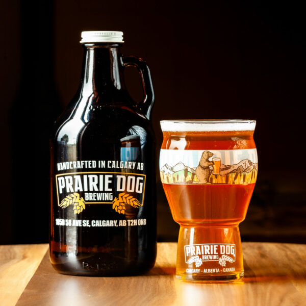 A 946mL howler jug of Prairie Dog Brewing Little Bear Kölsch with a 473mL draft pour in a branded beer glass.