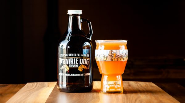 A 946mL howler fill and 473mL draft pour of Prairie Dog Brewing's Superb Radler orange cranberry wheat beer.