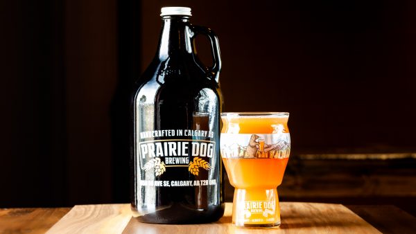 A 1.89L growler fill and 473mL draft pour of Prairie Dog Brewing's Superb Radler orange cranberry wheat beer.