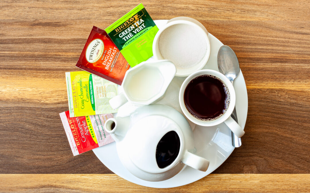 An assortment of tea options on a plate alongside Prairie Dog Brewing tea in a teapot, cup, with cream and sugar.