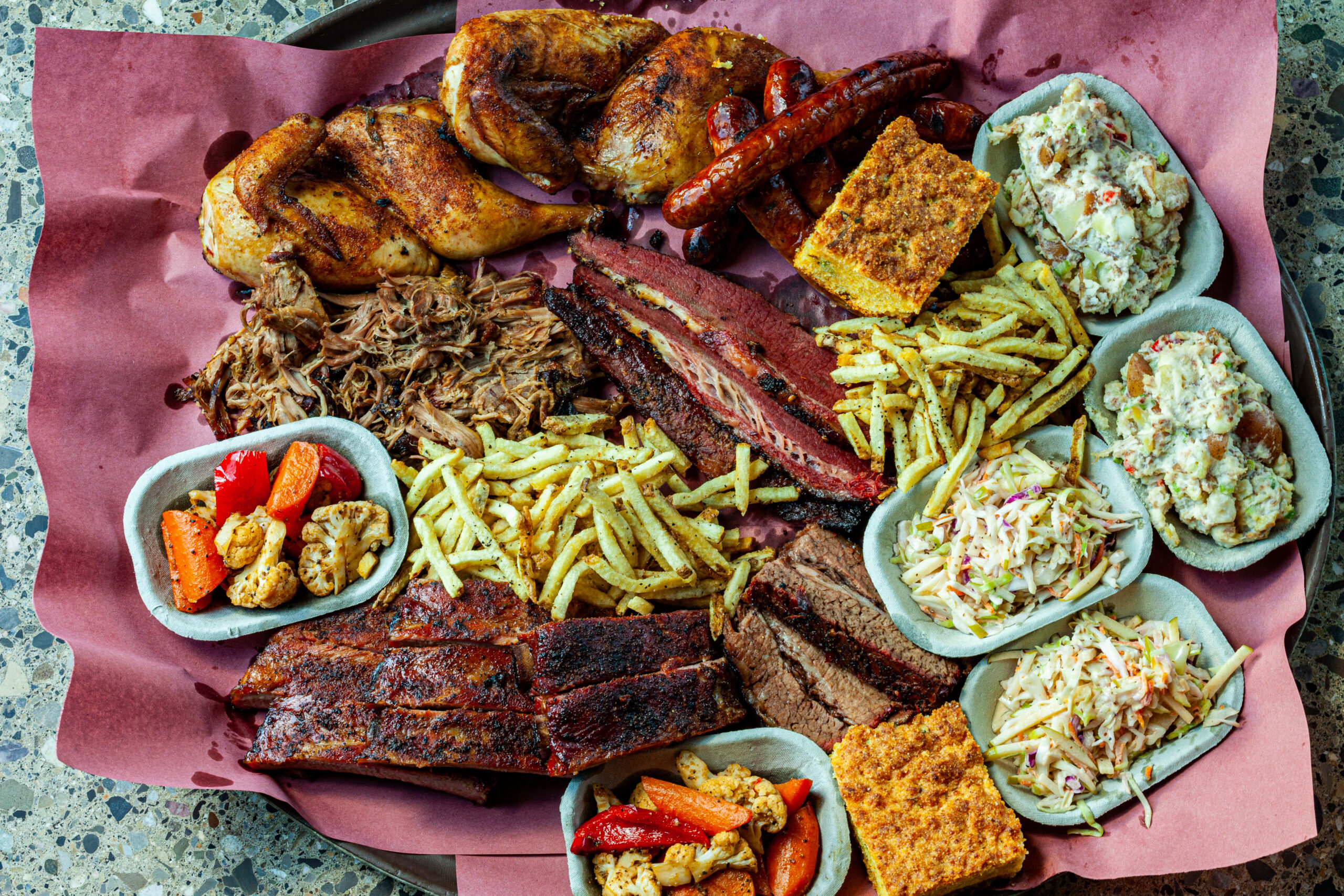 A huge platter full of Prairie Dog Brewing's signature BBQ combo The Fuller Pit featuring brisket, pastrami, pulled pork, pork side ribs, smoked chicken, chorizo sausages, fries, cornbread and sides.