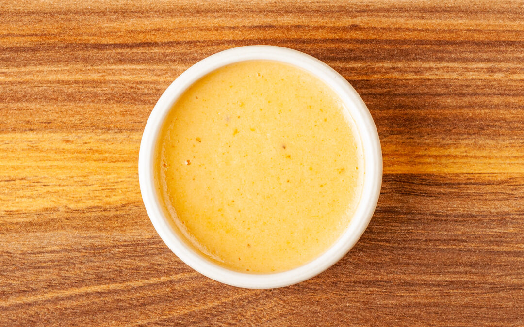 A ramekin of Prairie Dog Brewing's white cheddar cheese dip for use as a dipping sauce for soft pretzel bites or for add-on to any other menu item that needs a cheesy kick.