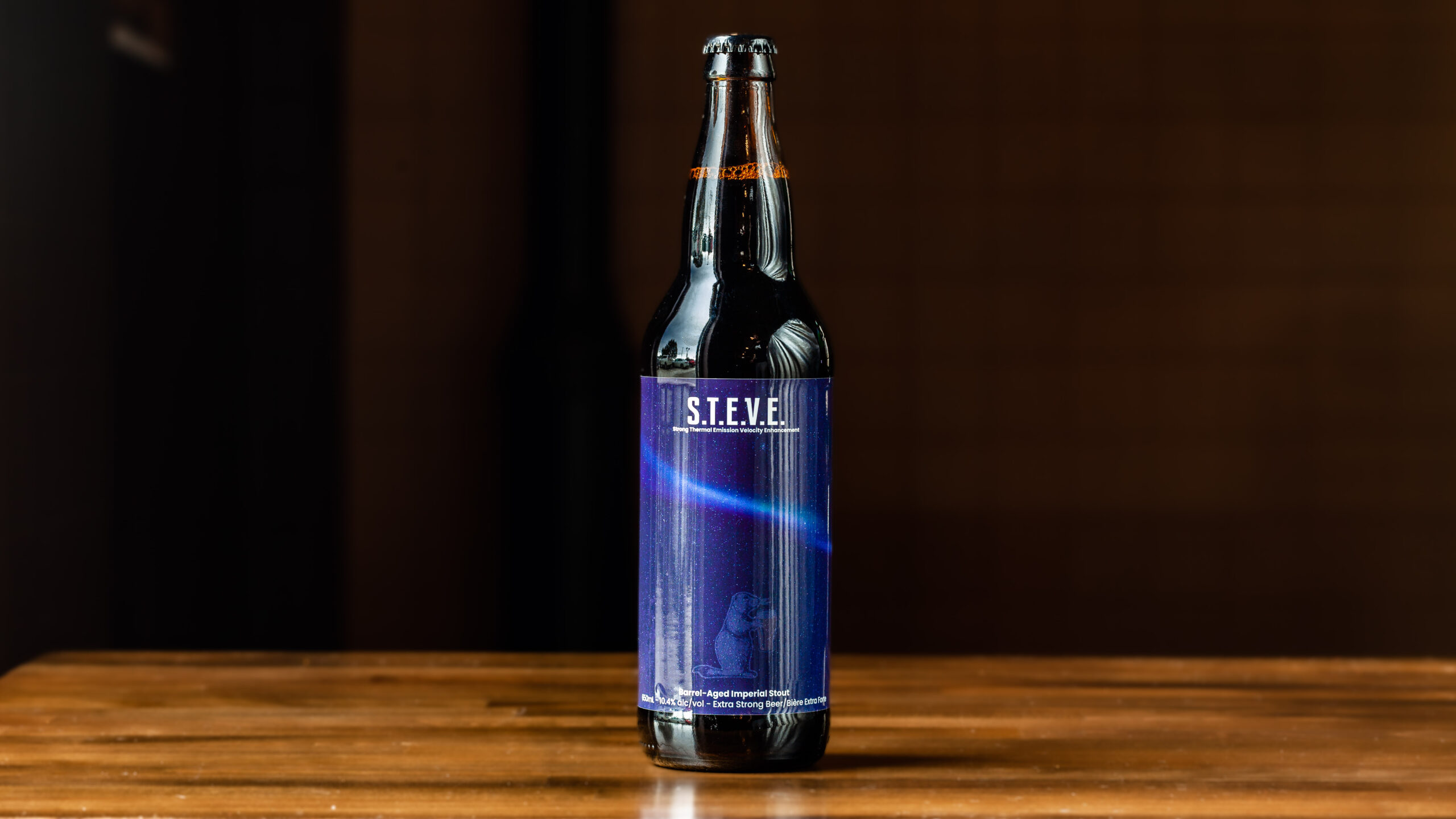 STEVE 650mL Bomber Bottle Barrel-Aged Imperial Stout A 473-ml pint glass of brightly coloured beer next to a can of Prairie Dog Brewing You're Beautiful Blueberry Lemon Sour Beer in full colour wrapped label.