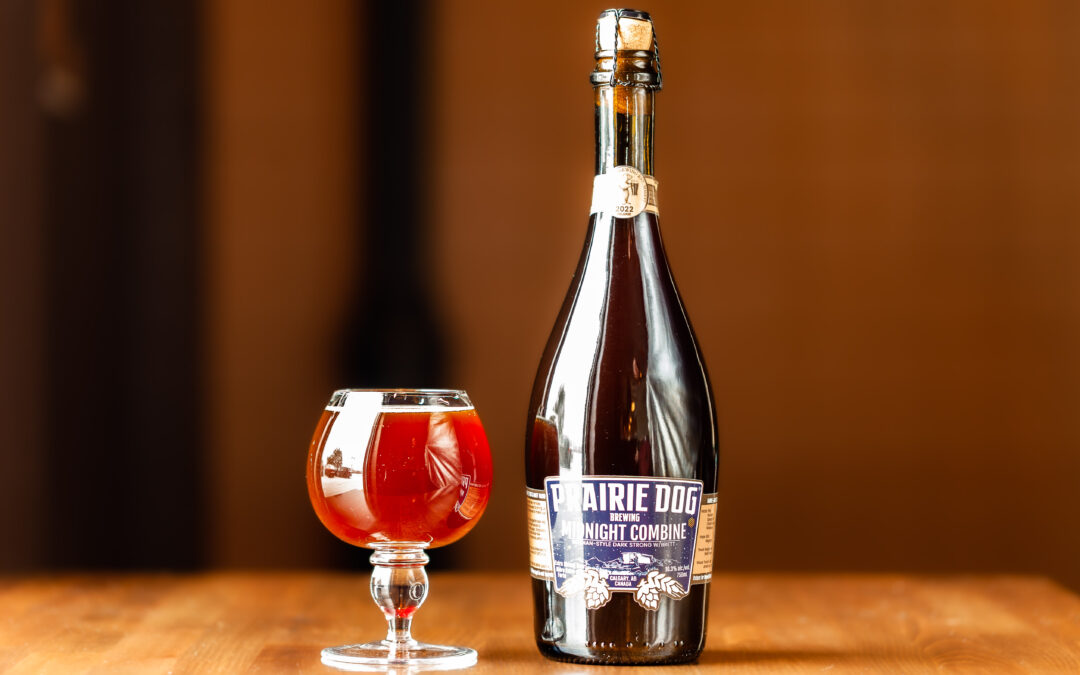 A 300ml Tulip Glass and 750ml Bottle of Prairie Dog Brewing's 2022 Midnight Combine Barrel-Aged Belgian Dark Strong Ale