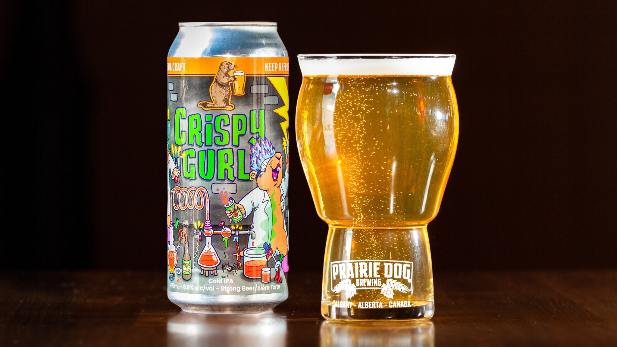 Prairie Dog Brewing and XhAle Brew Co. collab beer Crispy Gurl, a Cold IPA, in a 473mL can beside a pour of the same beer in a Prairie Dog Brewing beer glass.